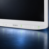 SONY-LMD-27M1MD surgical monitor, front detail view of the Sony logo and touch controls, white housing and black screen against a dark blue studio background.